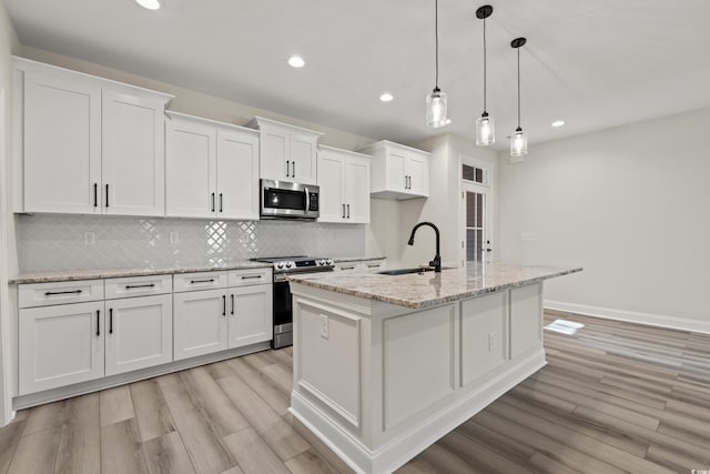 kitchen with white cabinets, stainless steel appliances, and a center island with sink