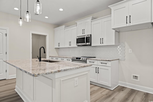 kitchen with a center island with sink, pendant lighting, white cabinetry, and appliances with stainless steel finishes