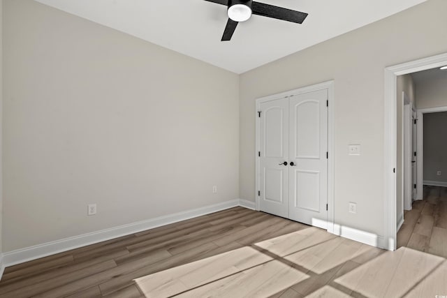 unfurnished bedroom featuring ceiling fan, a closet, and hardwood / wood-style flooring