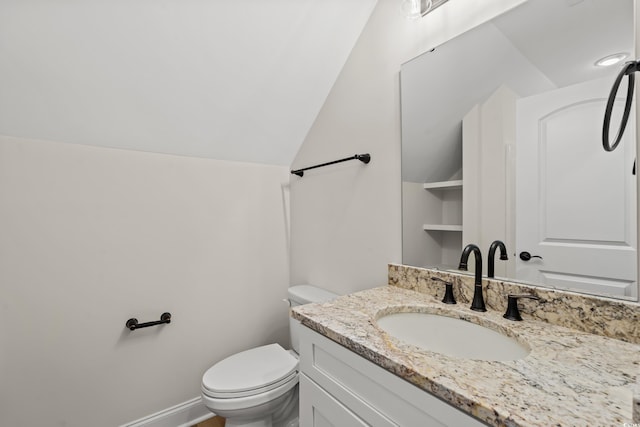 bathroom with toilet, vanity, and vaulted ceiling