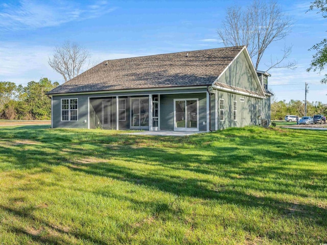 rear view of property featuring a sunroom, a patio, and a lawn