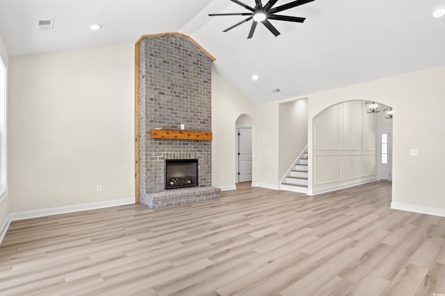 unfurnished living room featuring vaulted ceiling, light hardwood / wood-style floors, a brick fireplace, and ceiling fan