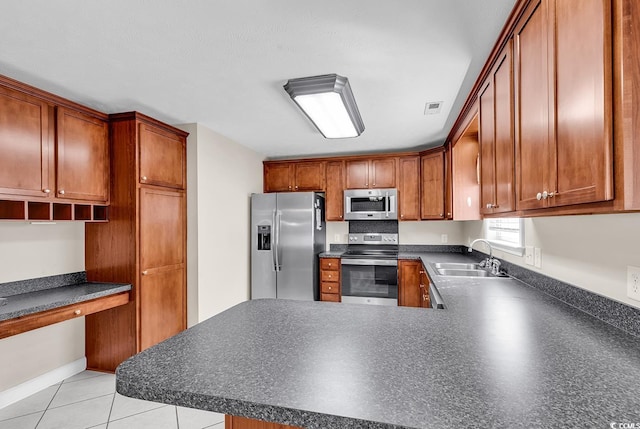 kitchen featuring dark countertops, visible vents, appliances with stainless steel finishes, built in study area, and a sink