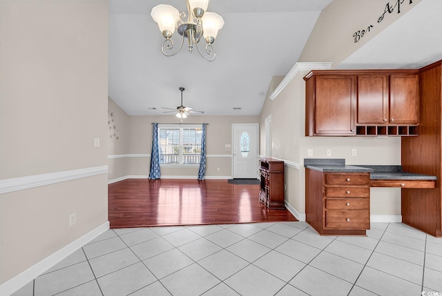 kitchen featuring dark countertops, brown cabinets, built in desk, and light tile patterned floors