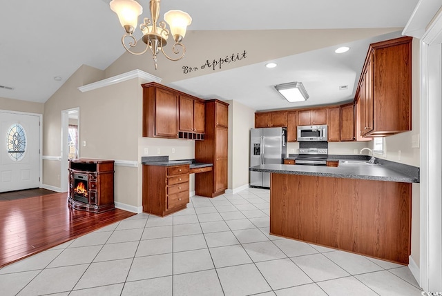 kitchen featuring vaulted ceiling, appliances with stainless steel finishes, dark countertops, and brown cabinets