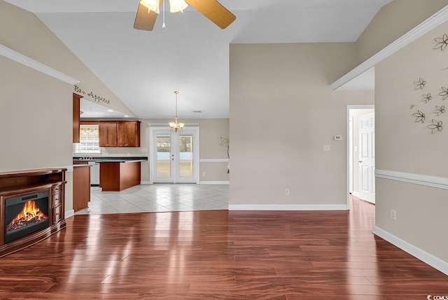 unfurnished living room featuring light wood-style floors, a glass covered fireplace, baseboards, and ceiling fan with notable chandelier