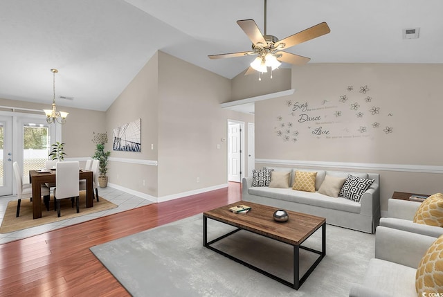 living area with high vaulted ceiling, wood finished floors, visible vents, and baseboards