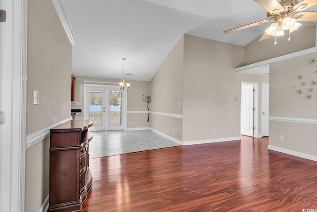 living area featuring lofted ceiling, baseboards, wood finished floors, and ceiling fan with notable chandelier