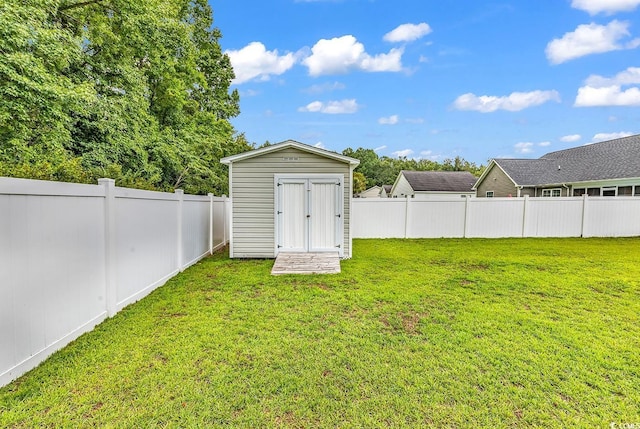 view of yard featuring a fenced backyard, a shed, and an outbuilding