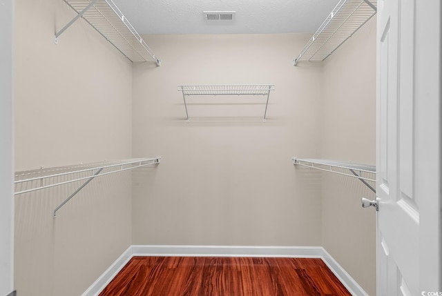 walk in closet featuring dark wood finished floors and visible vents