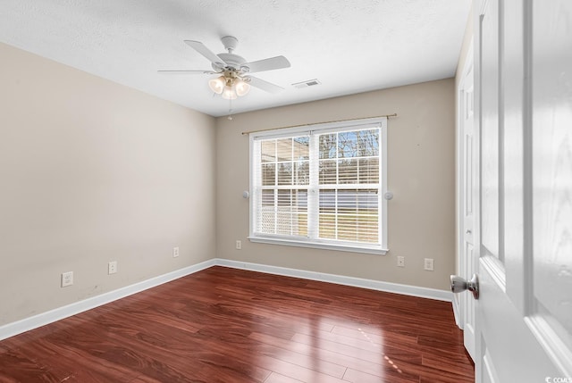 spare room featuring visible vents, a textured ceiling, baseboards, and wood finished floors