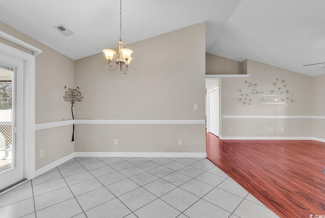 empty room with baseboards, visible vents, light wood-style flooring, vaulted ceiling, and a notable chandelier