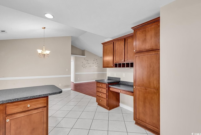 kitchen featuring dark countertops, light tile patterned floors, built in desk, and lofted ceiling