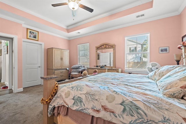 carpeted bedroom with ceiling fan, a tray ceiling, and ornamental molding