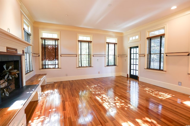 unfurnished living room featuring light hardwood / wood-style flooring, ornamental molding, and plenty of natural light