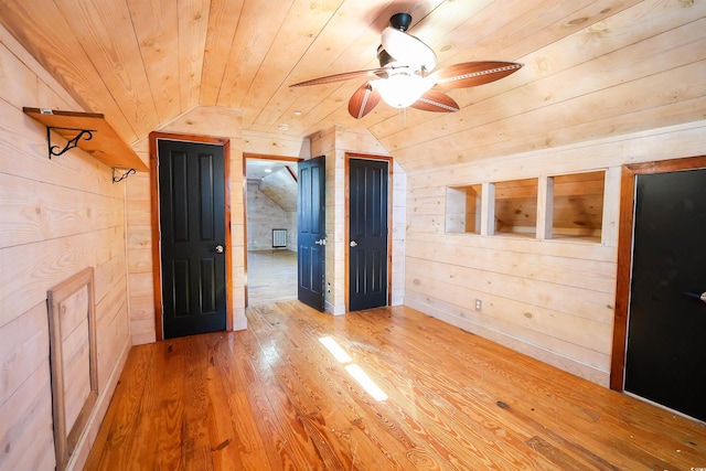 unfurnished room featuring wood walls, vaulted ceiling, wooden ceiling, ceiling fan, and hardwood / wood-style floors