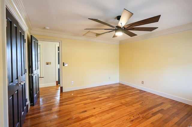 empty room featuring hardwood / wood-style flooring, ornamental molding, and ceiling fan