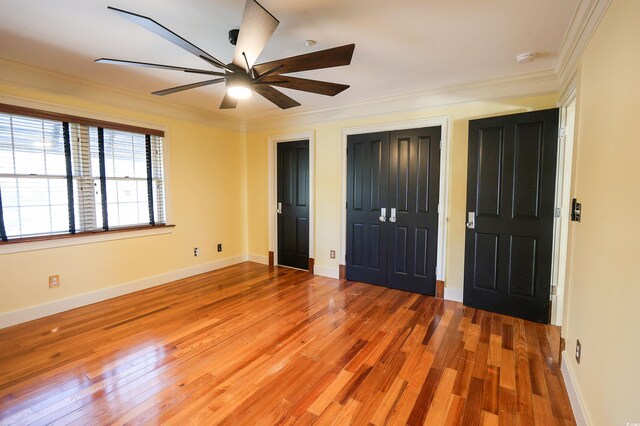 unfurnished bedroom featuring multiple closets, ceiling fan, ornamental molding, and light wood-type flooring