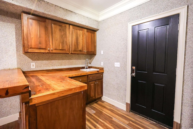 kitchen with crown molding, butcher block counters, sink, and hardwood / wood-style flooring