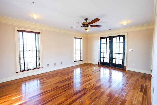 empty room featuring french doors, ornamental molding, wood-type flooring, and a wealth of natural light