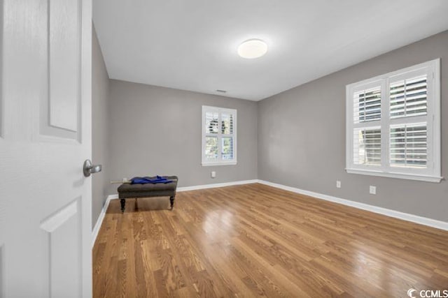 unfurnished room featuring wood-type flooring and a healthy amount of sunlight