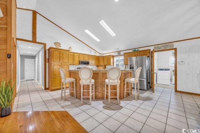 kitchen with a breakfast bar area, a center island, washer / dryer, and appliances with stainless steel finishes