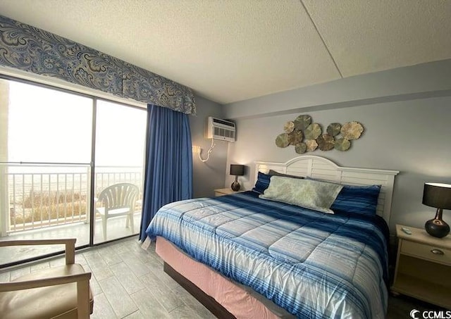 bedroom with light hardwood / wood-style flooring, access to exterior, a textured ceiling, and a wall unit AC