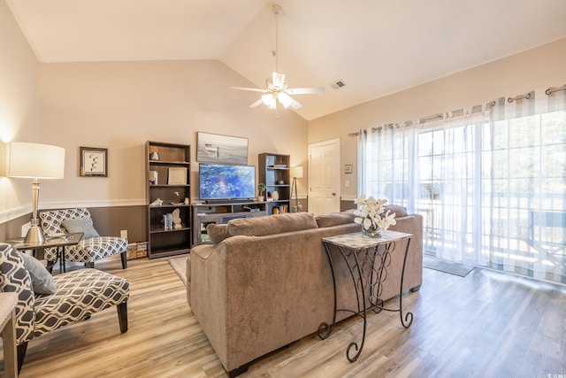 living room with a ceiling fan, visible vents, vaulted ceiling, and light wood finished floors