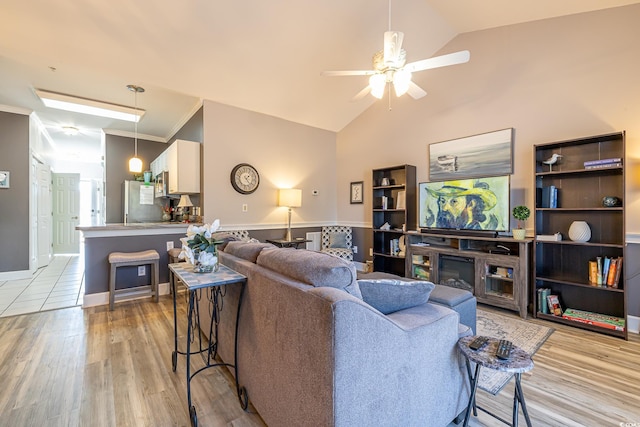 living area featuring crown molding, light wood-type flooring, ceiling fan, and lofted ceiling