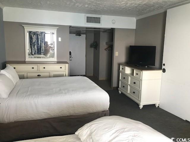 bedroom featuring dark colored carpet and a textured ceiling