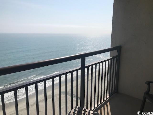 balcony with a water view and a view of the beach