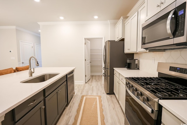 kitchen with sink, appliances with stainless steel finishes, light hardwood / wood-style floors, white cabinets, and decorative backsplash