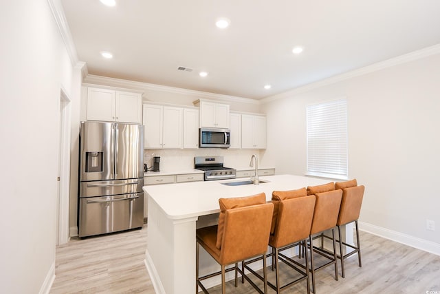 kitchen with a center island with sink, a breakfast bar area, white cabinets, and appliances with stainless steel finishes