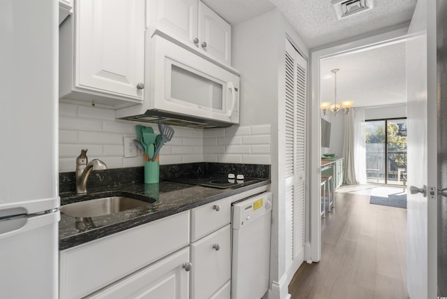 kitchen with dark stone countertops, sink, white appliances, and white cabinets