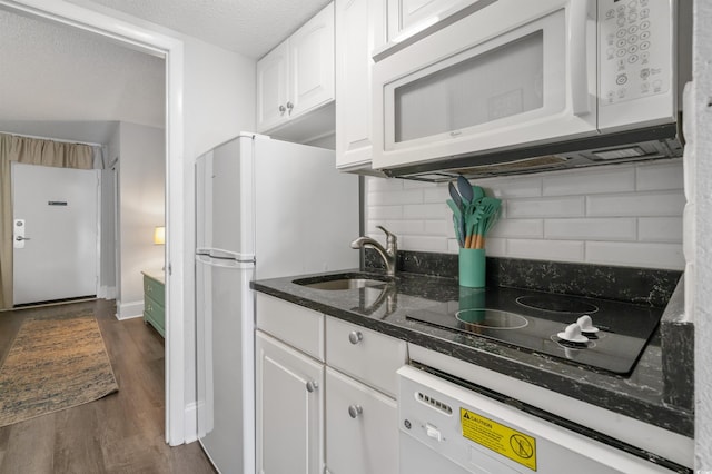 kitchen with sink, white cabinetry, dark hardwood / wood-style flooring, white appliances, and dark stone counters