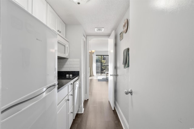 kitchen featuring white appliances, dark hardwood / wood-style floors, tasteful backsplash, a textured ceiling, and white cabinets