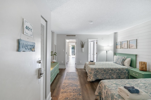 bedroom featuring dark hardwood / wood-style floors, a textured ceiling, and wood walls