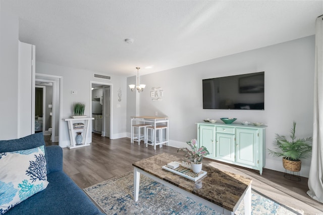 living room featuring hardwood / wood-style floors, a textured ceiling, and an inviting chandelier