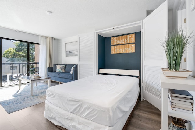 bedroom with hardwood / wood-style flooring, access to exterior, and a textured ceiling