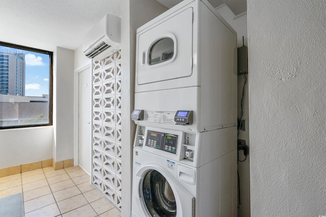 washroom with stacked washer and clothes dryer, a textured ceiling, a wall unit AC, and light tile patterned floors