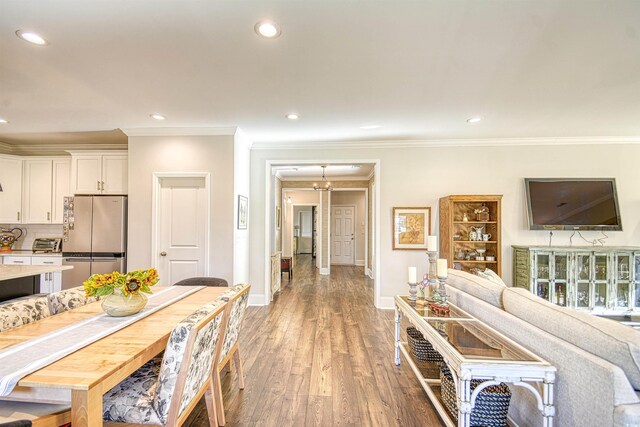 interior space featuring stainless steel fridge, white cabinets, hardwood / wood-style flooring, and ornamental molding