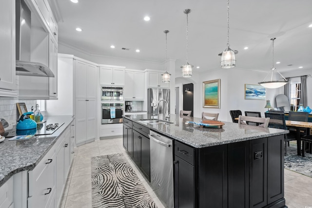 kitchen featuring sink, wall chimney range hood, pendant lighting, a spacious island, and appliances with stainless steel finishes