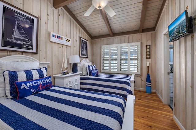 bedroom with ceiling fan, light hardwood / wood-style flooring, lofted ceiling with beams, and wood walls