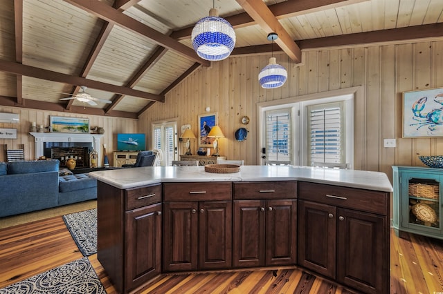 kitchen featuring lofted ceiling with beams, ceiling fan, decorative light fixtures, a kitchen island, and dark brown cabinets