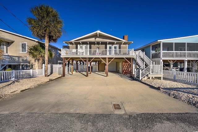 raised beach house featuring a sunroom, covered porch, and a carport