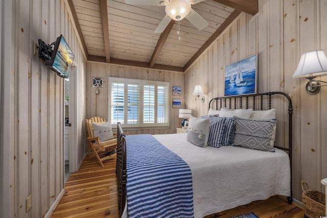 bedroom with ceiling fan, hardwood / wood-style flooring, wooden ceiling, vaulted ceiling with beams, and wood walls