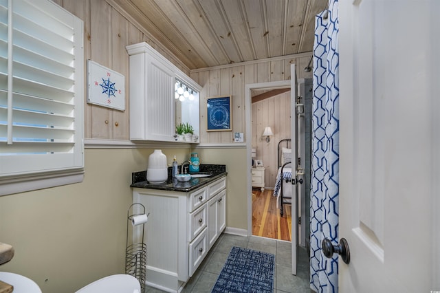 bathroom featuring tile patterned floors, vanity, wood ceiling, and wooden walls