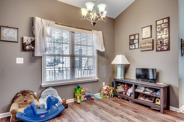 recreation room featuring a chandelier, vaulted ceiling, and hardwood / wood-style flooring