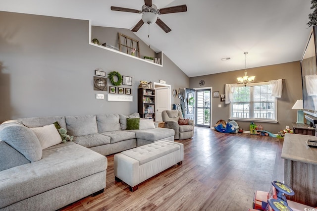 living room featuring vaulted ceiling, wood-type flooring, and ceiling fan with notable chandelier