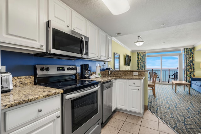 kitchen with white cabinets, light tile patterned flooring, ornamental molding, and stainless steel appliances